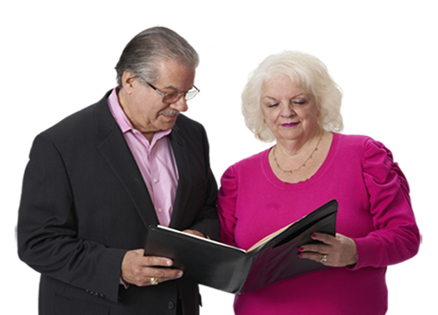 a man and woman standing and looking down at a book together